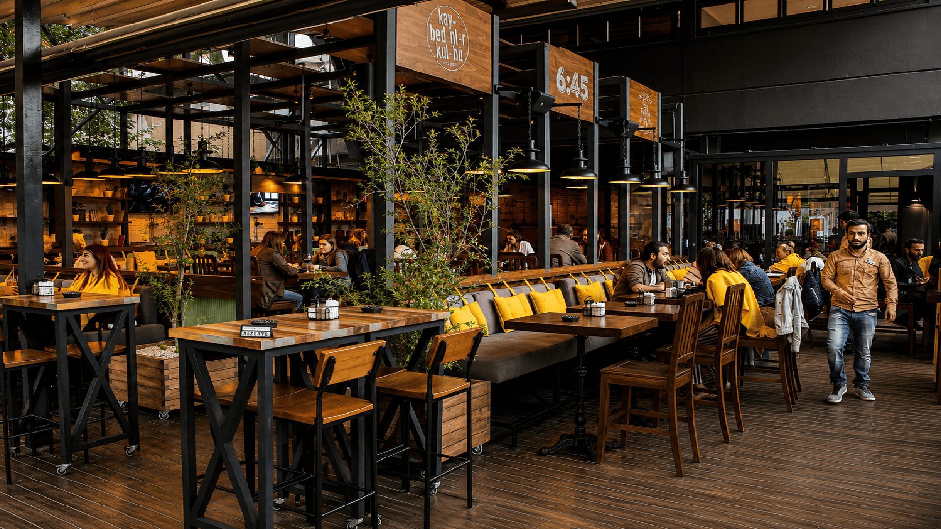6:45 Pub'da siyah çelik çerçeveler ve ahşap masalar