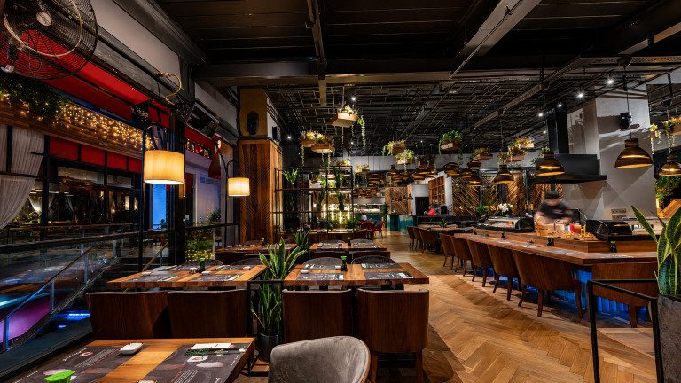 Sushi restoranı tasarımı: Sushinami salonunda uzun bar, ahşap masalar ve endüstriyel tavan