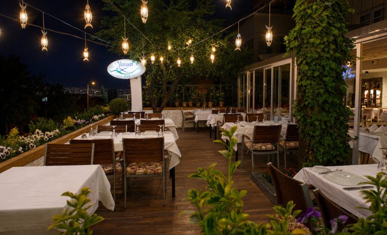 Ankara balık restoranı tasarımı: Yosun Balık Gaziosmanpaşa, ağaçlar arasında sarkan aydınlatmalı teras
