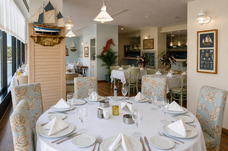 Balık restoranı iç mimarisi: Martı Balık salonunda yuvarlak masa, gemi maketi ve denizci temalı detaylar